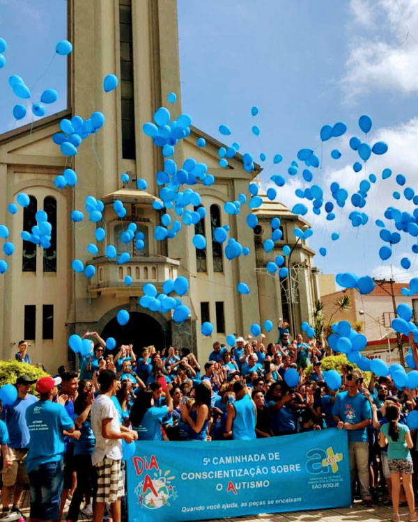 um grupo grande de pessoas soltando balões azuis na Praça da Matriz de São Roque